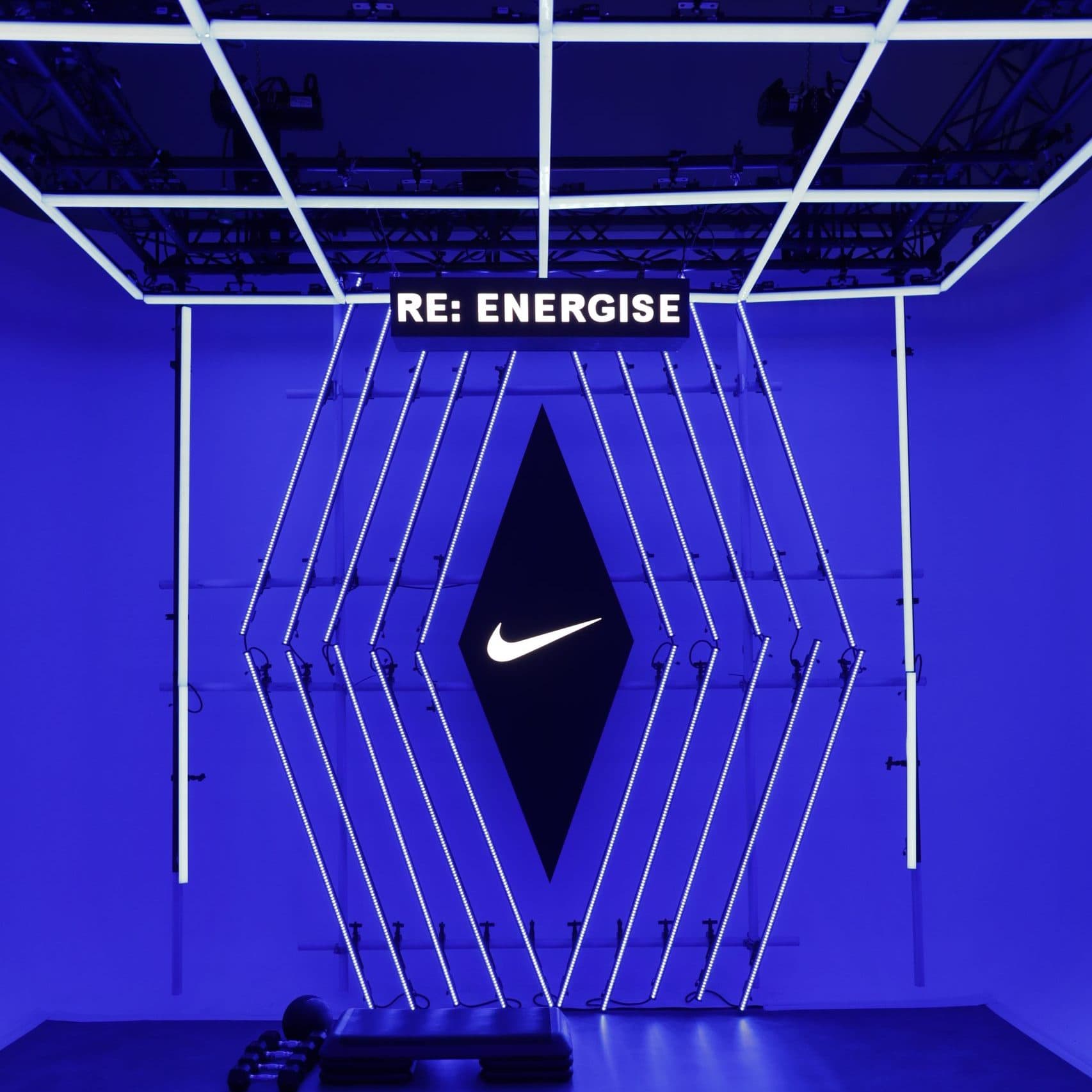 Neon white Nike logo on blue lit wall