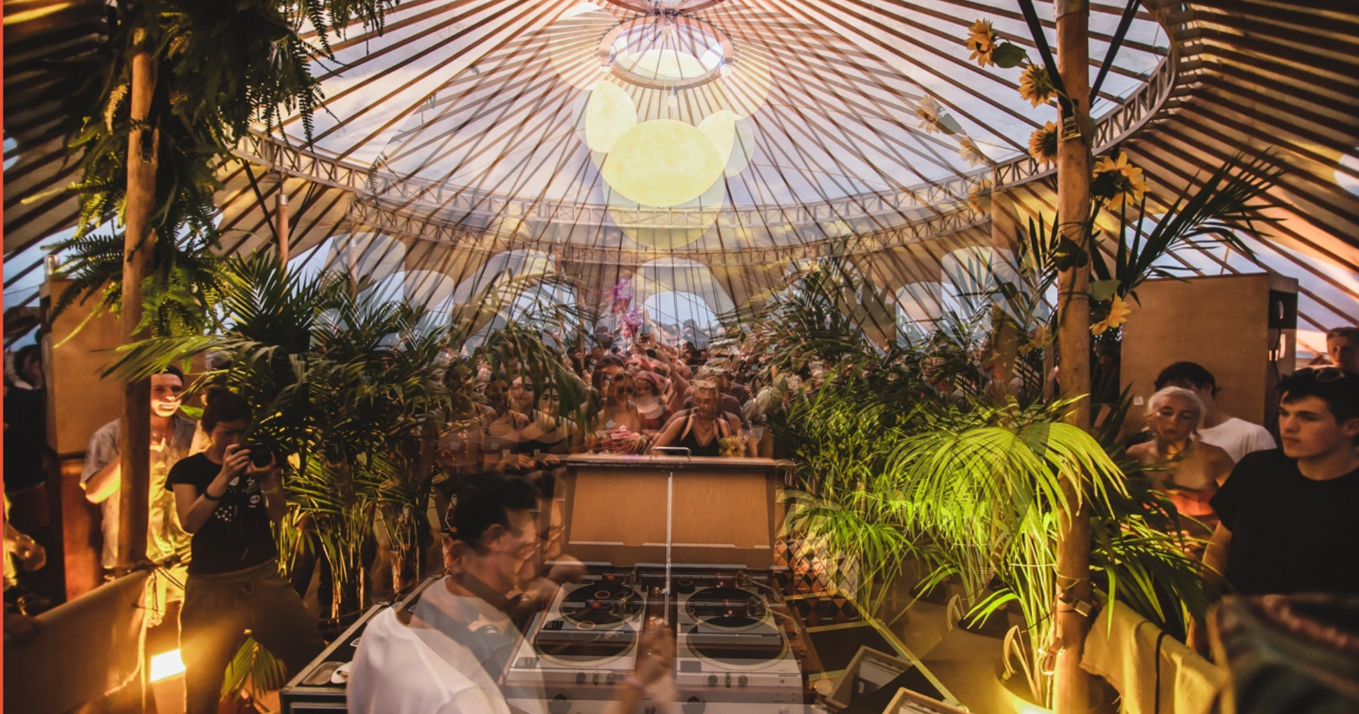 Crowd in a marquee by a DJ booth