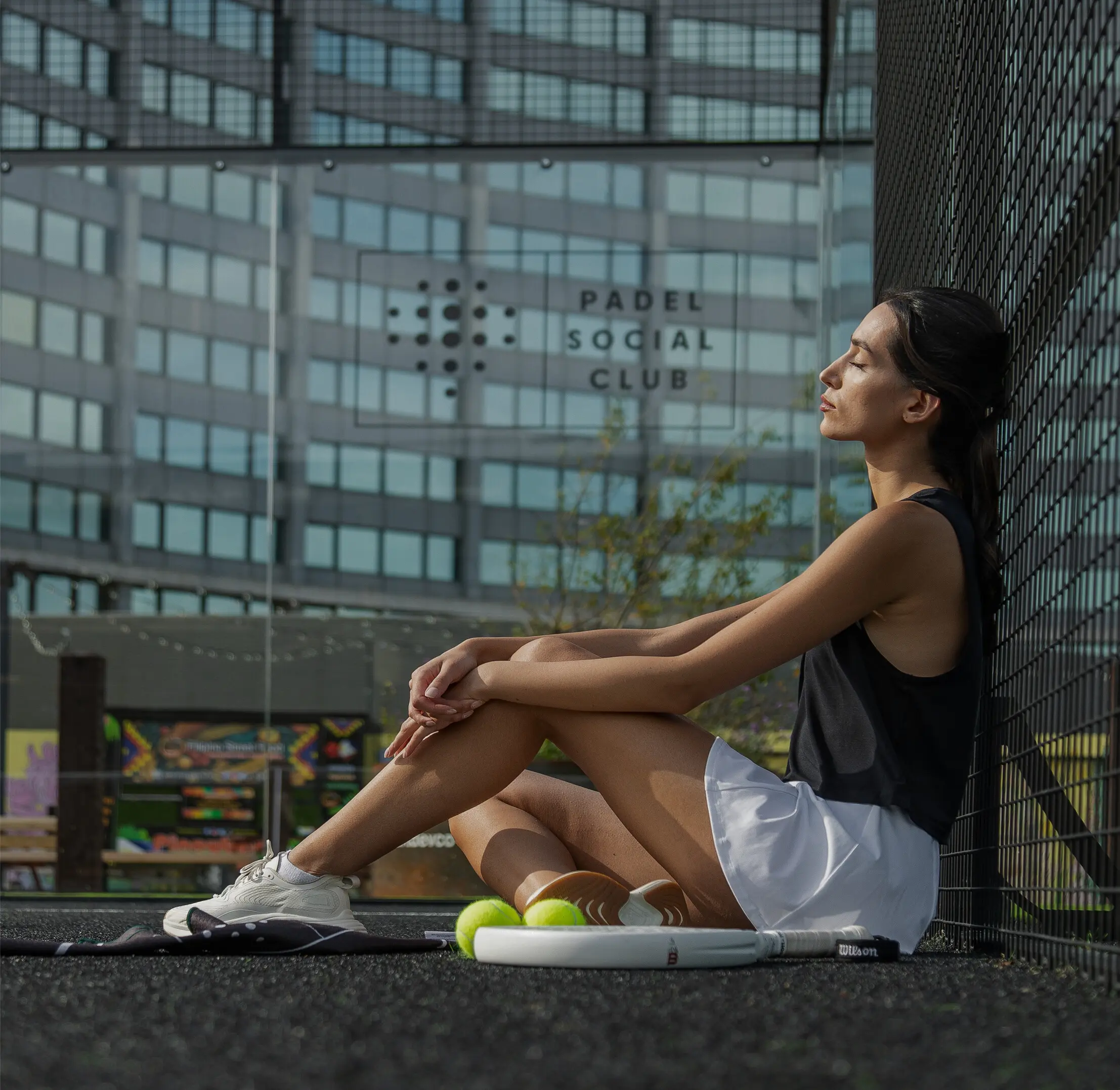 Female model sat on a Padel court