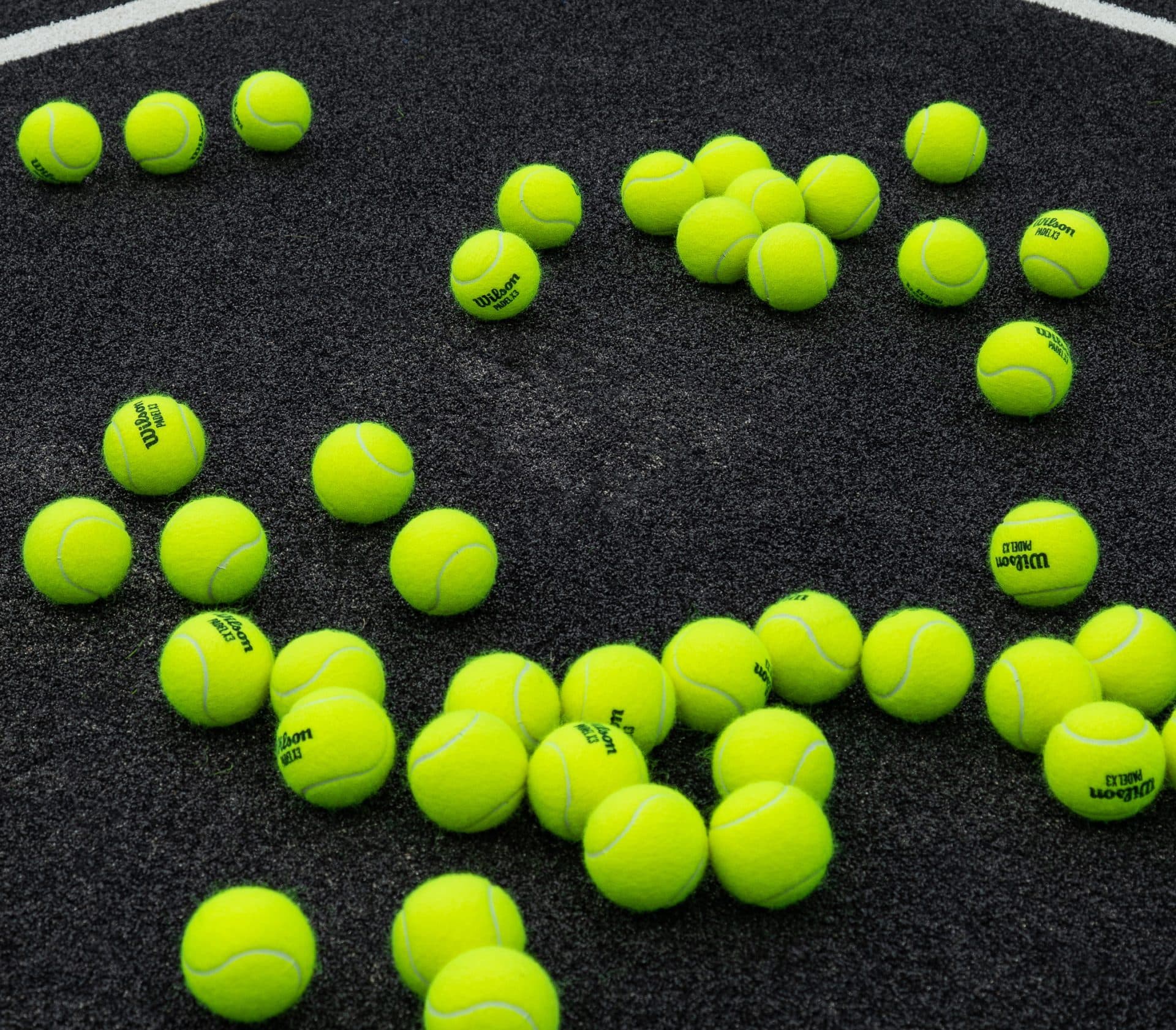 Neon padel balls on a court floor